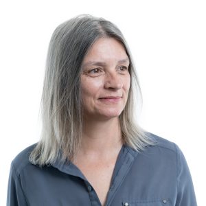 Headshot of a woman in a light blue shirt smiling away from the camera